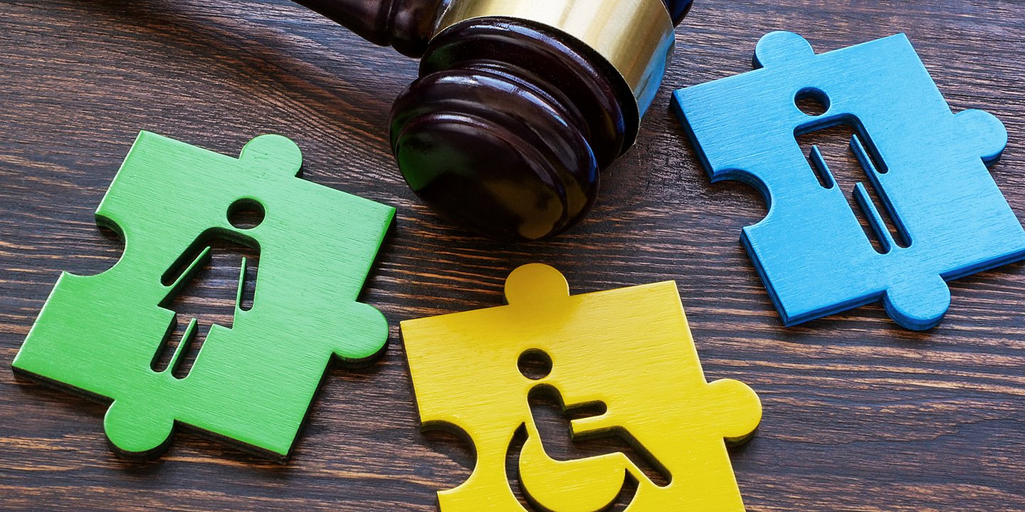 Foto: Drei Puzzleteile liegen nebeneinander: Ein Grünes mit einem Frauensymbol, ein Gelbes mit einem Rollstuhlfahrer-Symbol und ein Blaues mit einem Mann-Symbol.