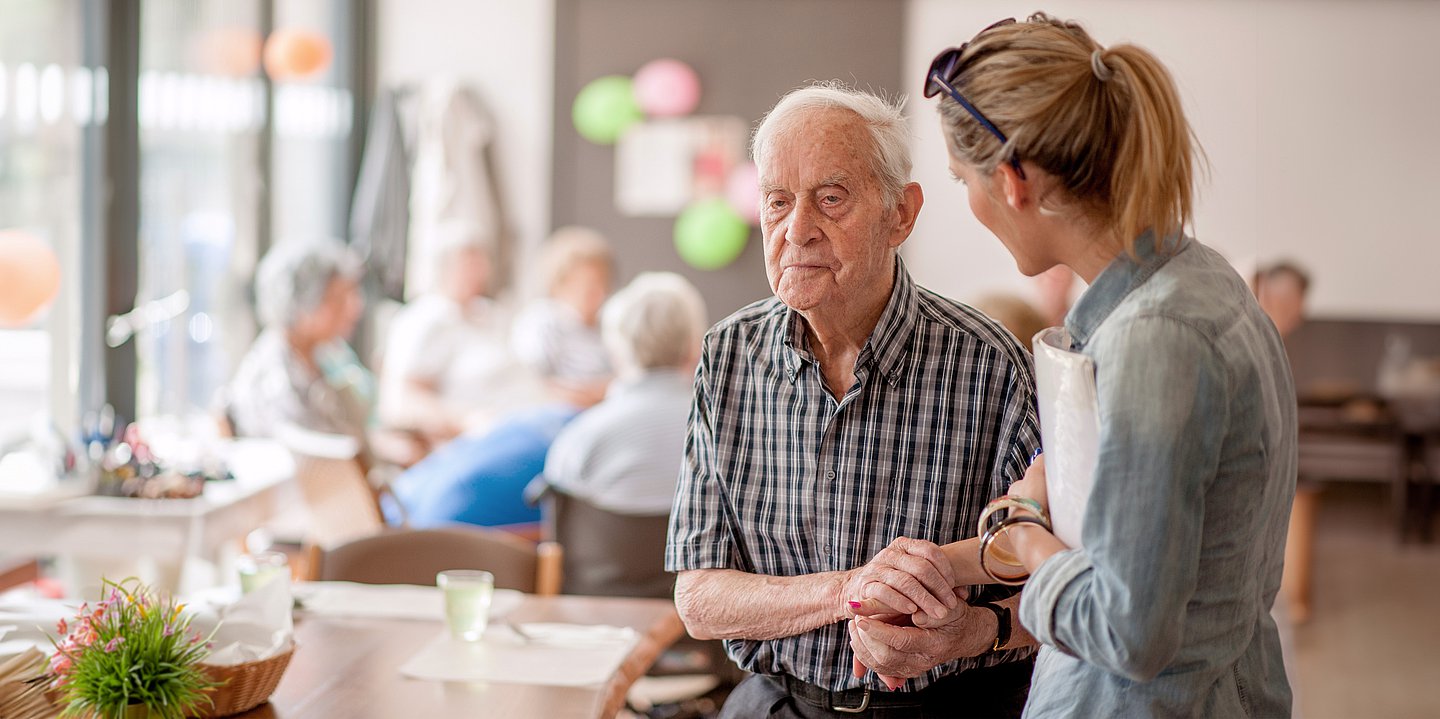 Foto: Eine Pflegekraft stützt einen älteren Herren