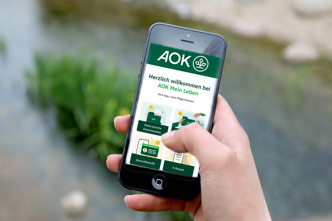 Eine Hand hält ein Smartphone, auf dem eine AOK-App läuft.