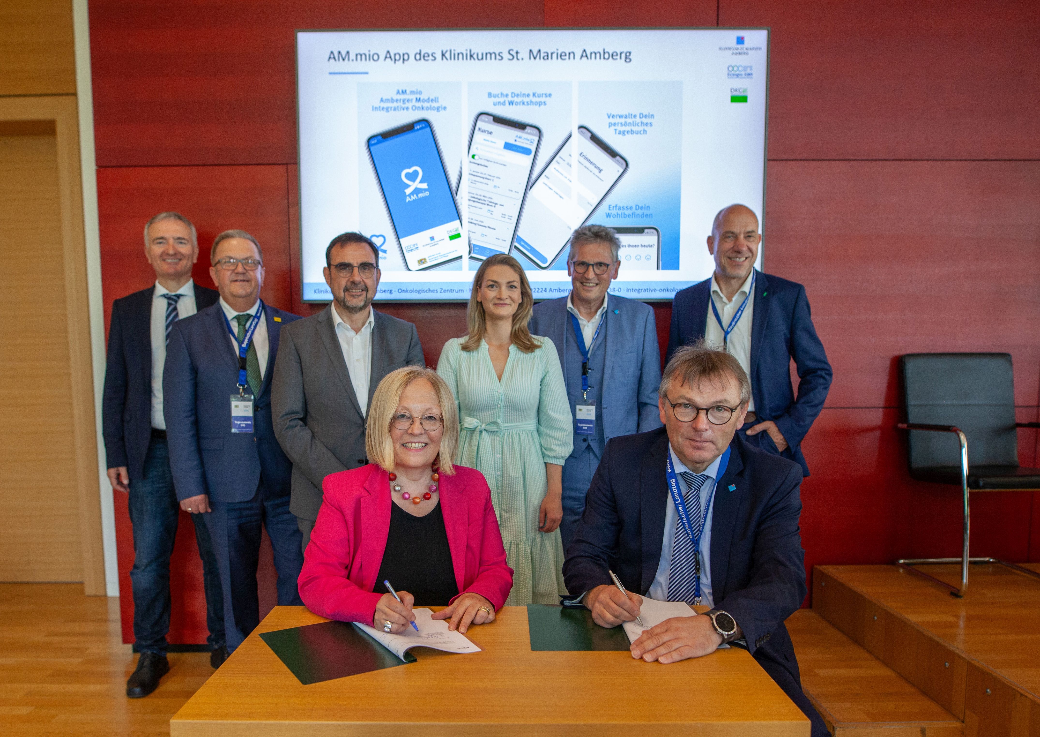 Auf dem Foto ist AOK Bayern-Vorständin Dr. Irmgard Stippler im roten Blazer sowie Judith Gerlach, Bayerische Gesundheitsministerin sowie ihr Vorgänger Klaus Holetschek und andere zu sehen