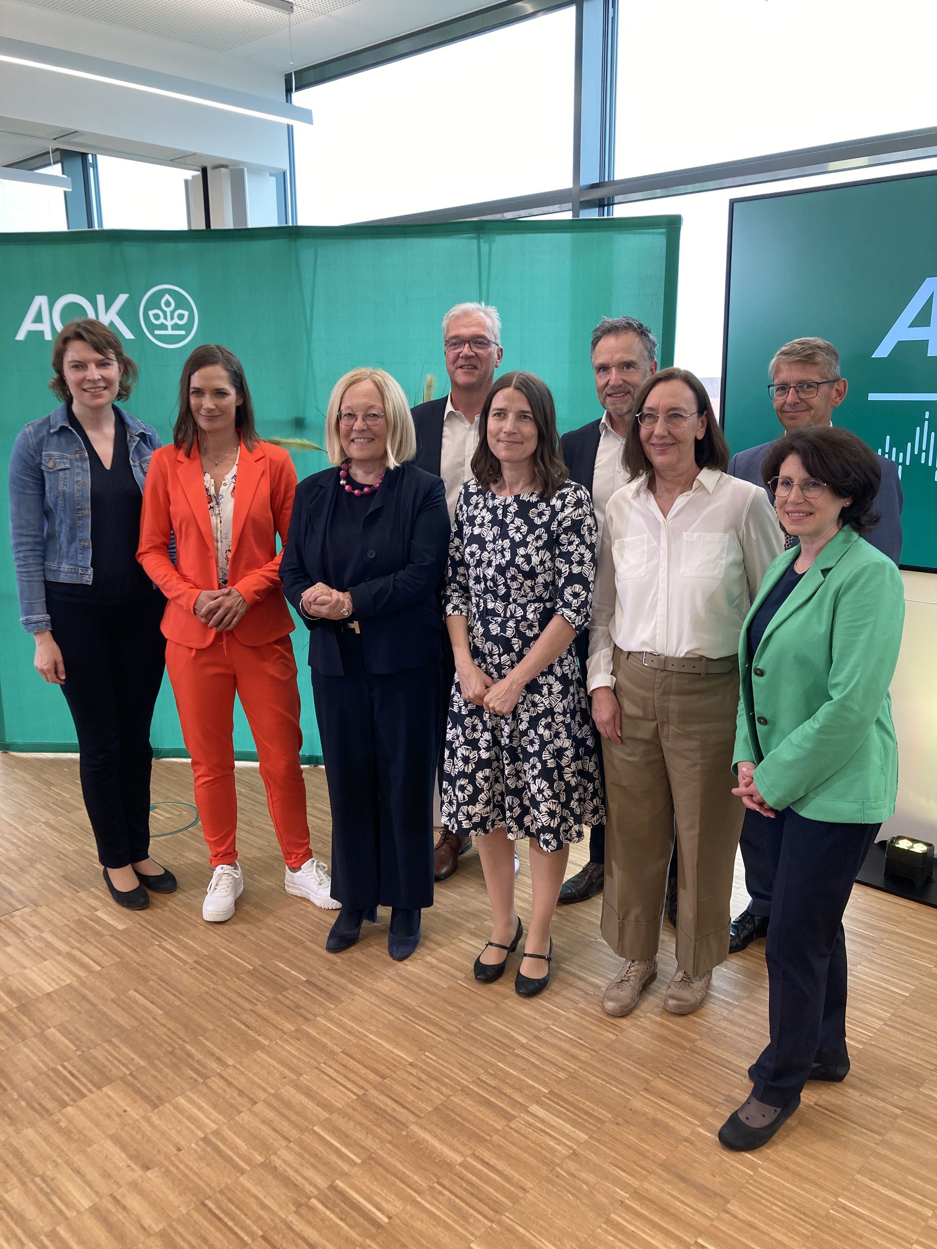 Im Foto v. l. n. r.: Emmi Zeulner (Mitglied des Deutschen Bundestages/CSU), Isabella Kroth (Moderatorin), Dr. Irmgard Stippler (Vorstandsvorsitzende der AOK Bayern), Georg Sigl-Lehner (Präsident der Vereinigung der Pflegenden, Bayern), Prof. Dr. Annika Herr (Direktorin des Instituts für Gesundheitsökonomie, Leibniz Universität Hannover), Dr. Eckart Schnabel (Leiter der Forschungsstelle Pflegeversicherung, GKV-SV Berlin), Prof. Dr. Gabriele Wilz (Leiterin der Abteilung klinisch-psychologische Intervention und der Forschungs- und Lehrambulanz, Friedrich-Schiller-Universität Jena), Dr. Bernhard Opolony (Leiter des Bereichs Pflege am Bayerische Staatsministerium für Gesundheit, Pflege und Prävention) und Alexandra Krist (Geschäftsbereichsleiterin Pflege der AOK Bayern)