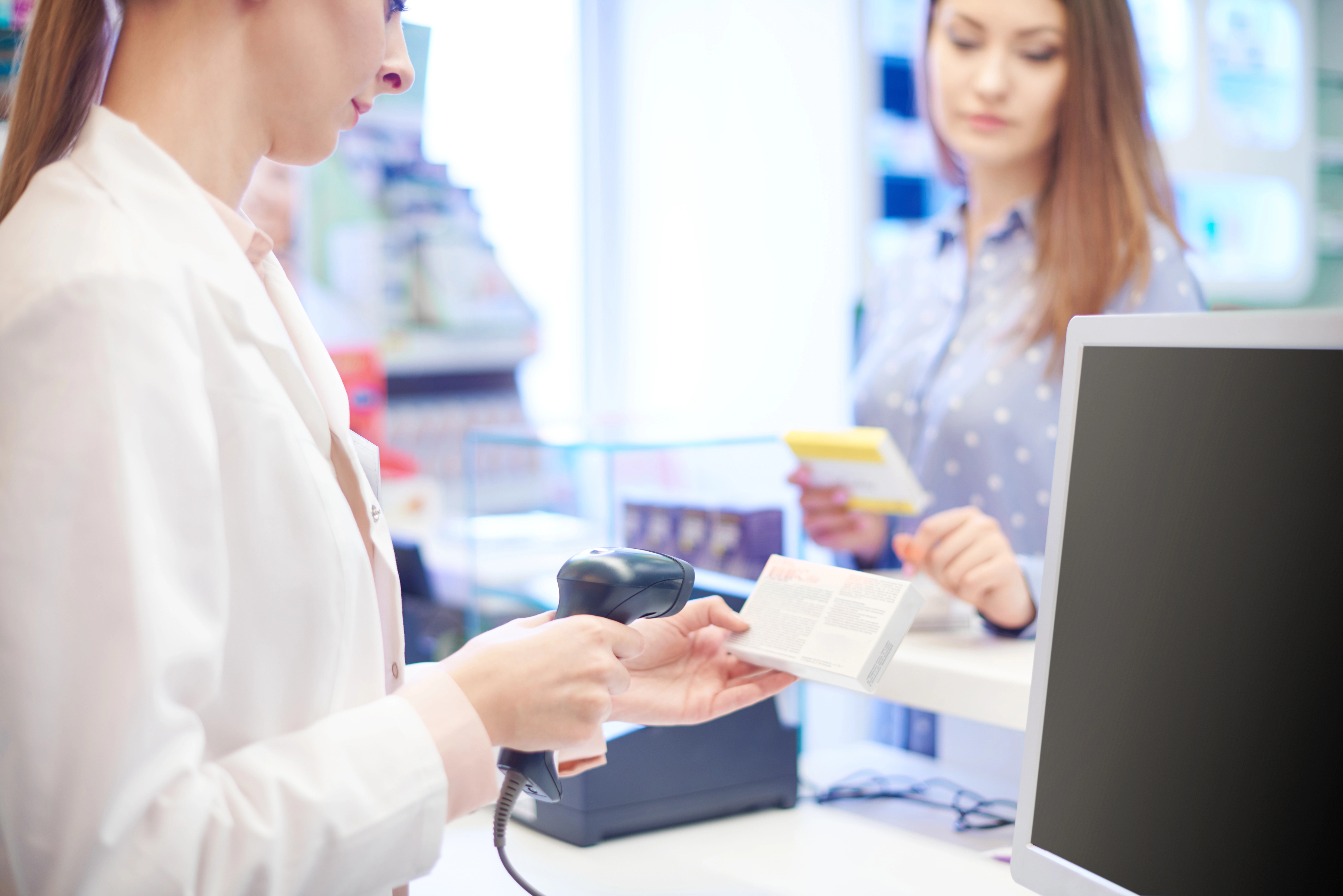 Das Bild zeigt eine Apothekerin, die für eine Kundin ein Medikament einscannt.