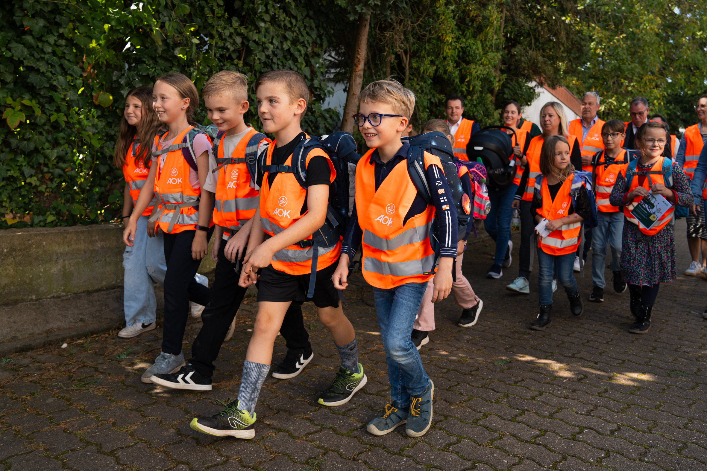 Grundschulkinder mit Warnwesten auf dem Schulweg.