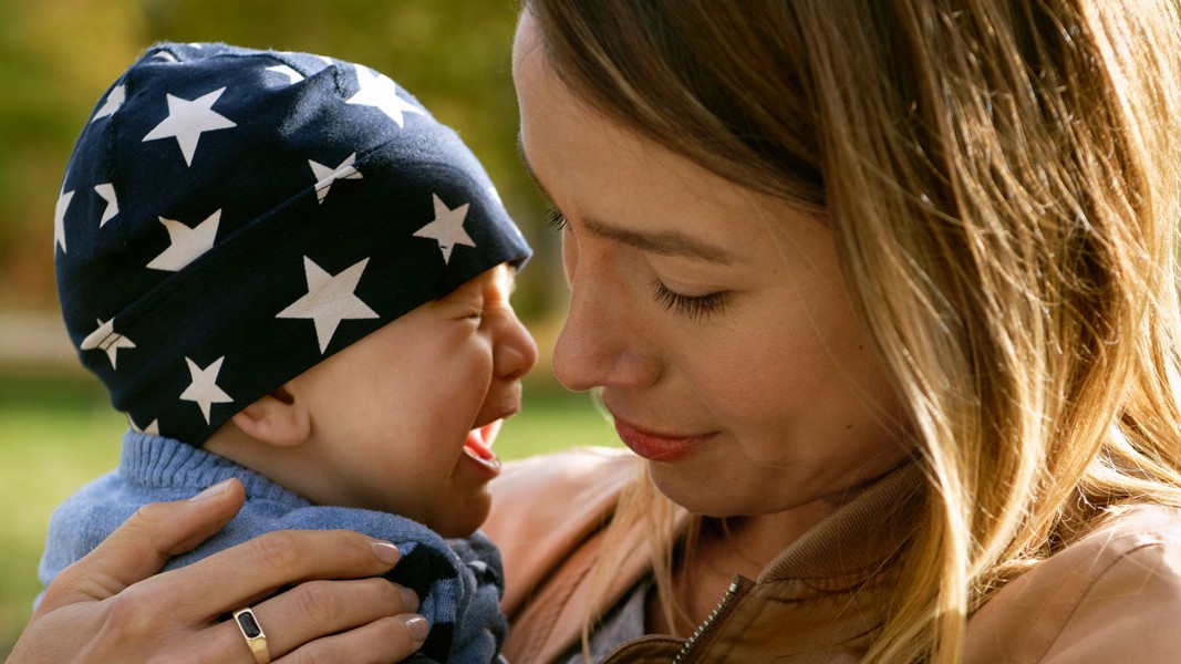 Eine Frau trägt ein schreiendes Baby.